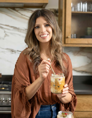 Christine in her kitchen holding a jar of overnight oats