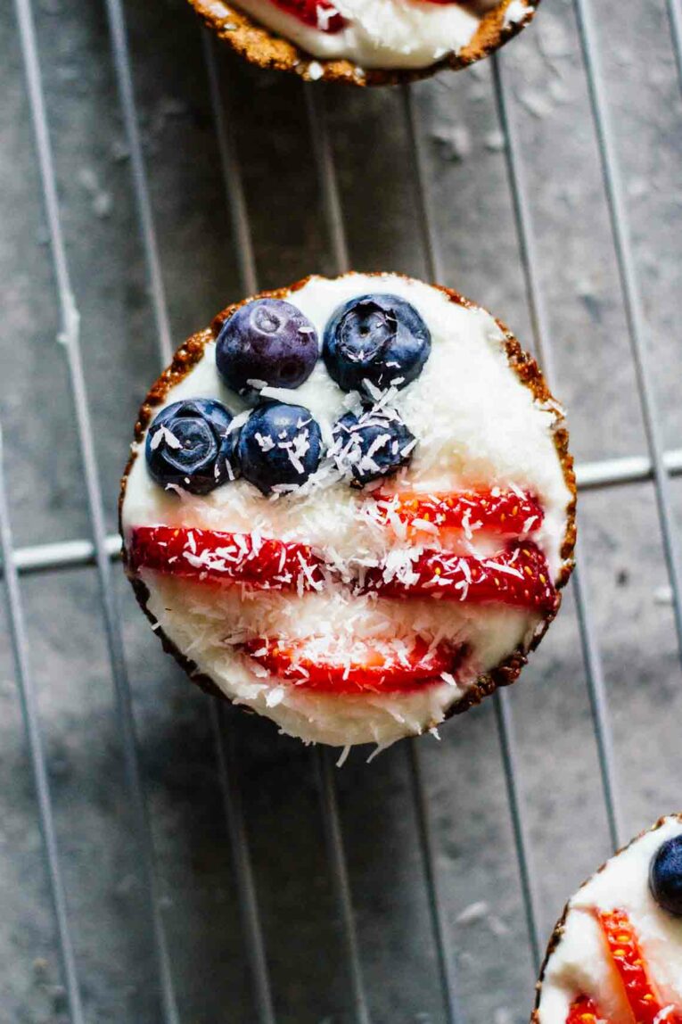 The cutest little Fruit Tarts made with blueberries and strawberries, perfect for Fourth of July! These patriotic tarts not only look the part but they taste incredible and better yet they're super healthy! #fruittarts #berrytarts Patriotic Mini Fruit Tarts close up on a cooling rack