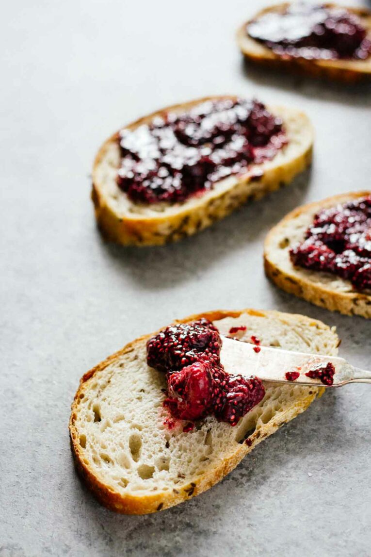 A close up of spreading chia seed jam on a slice of bread with a knife