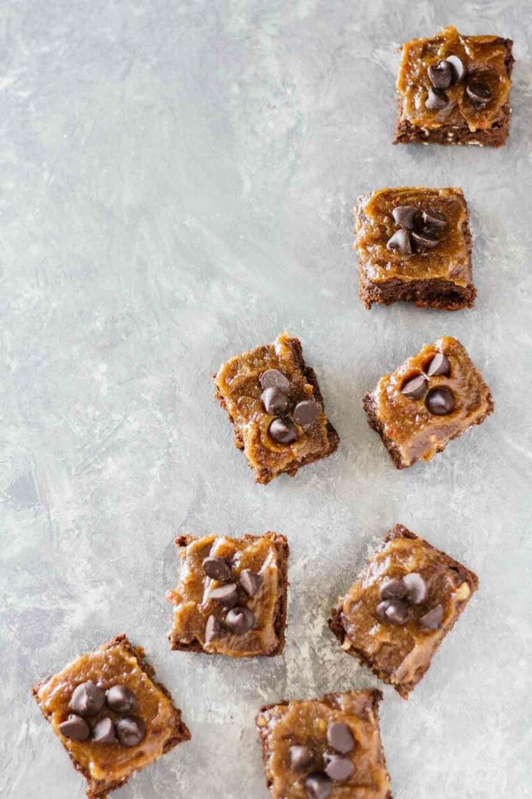 Overhead shot of several Healthy Chocolate Brownies w/ Date Caramel Sauce scattered on parchment paper