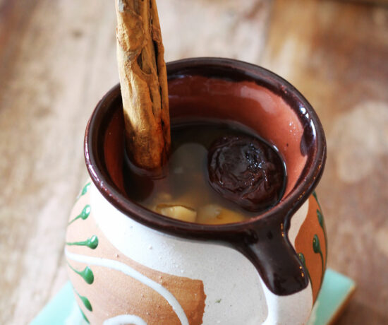 Mexican Ponche in a cozy cup with cinnamon stick.