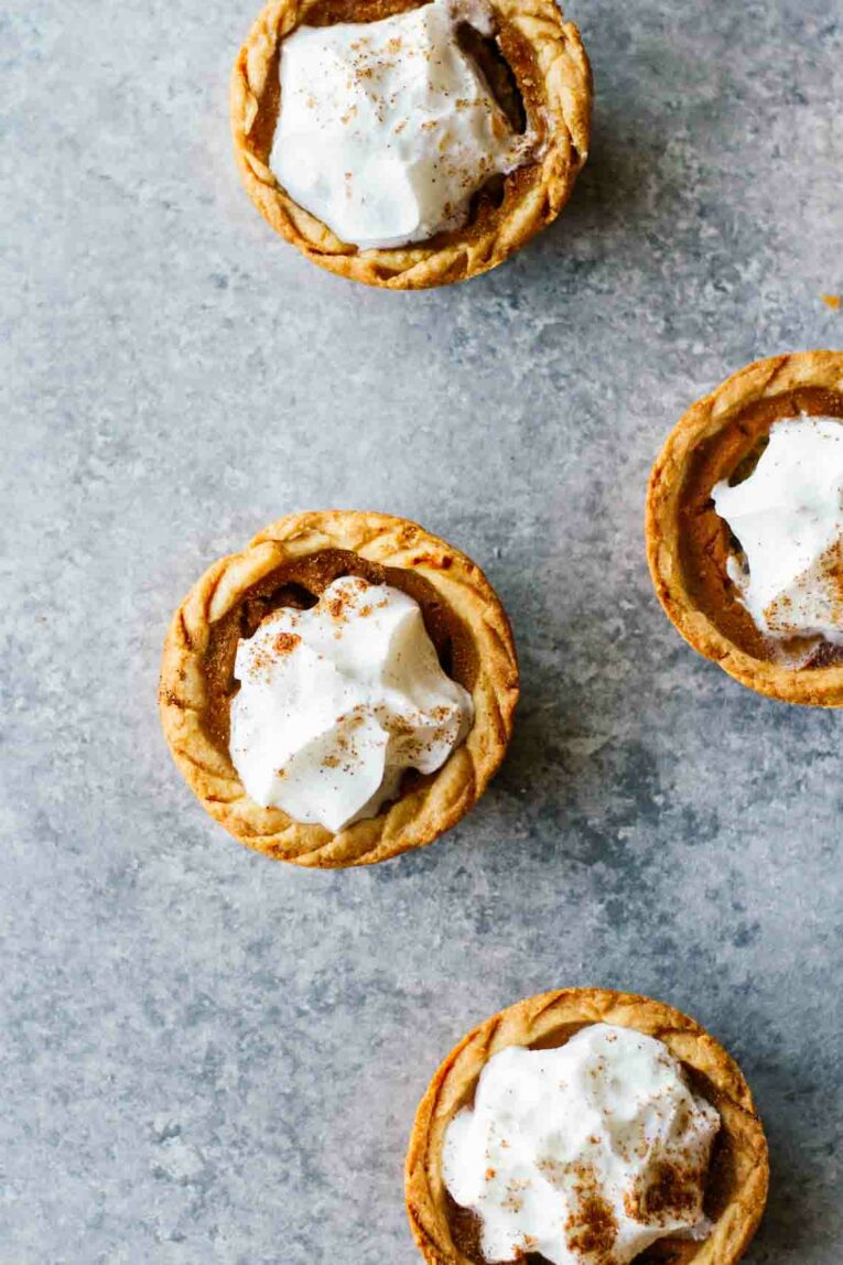 Mini Pumpkin Pies Topped with Whipped Cream on a Gray Table