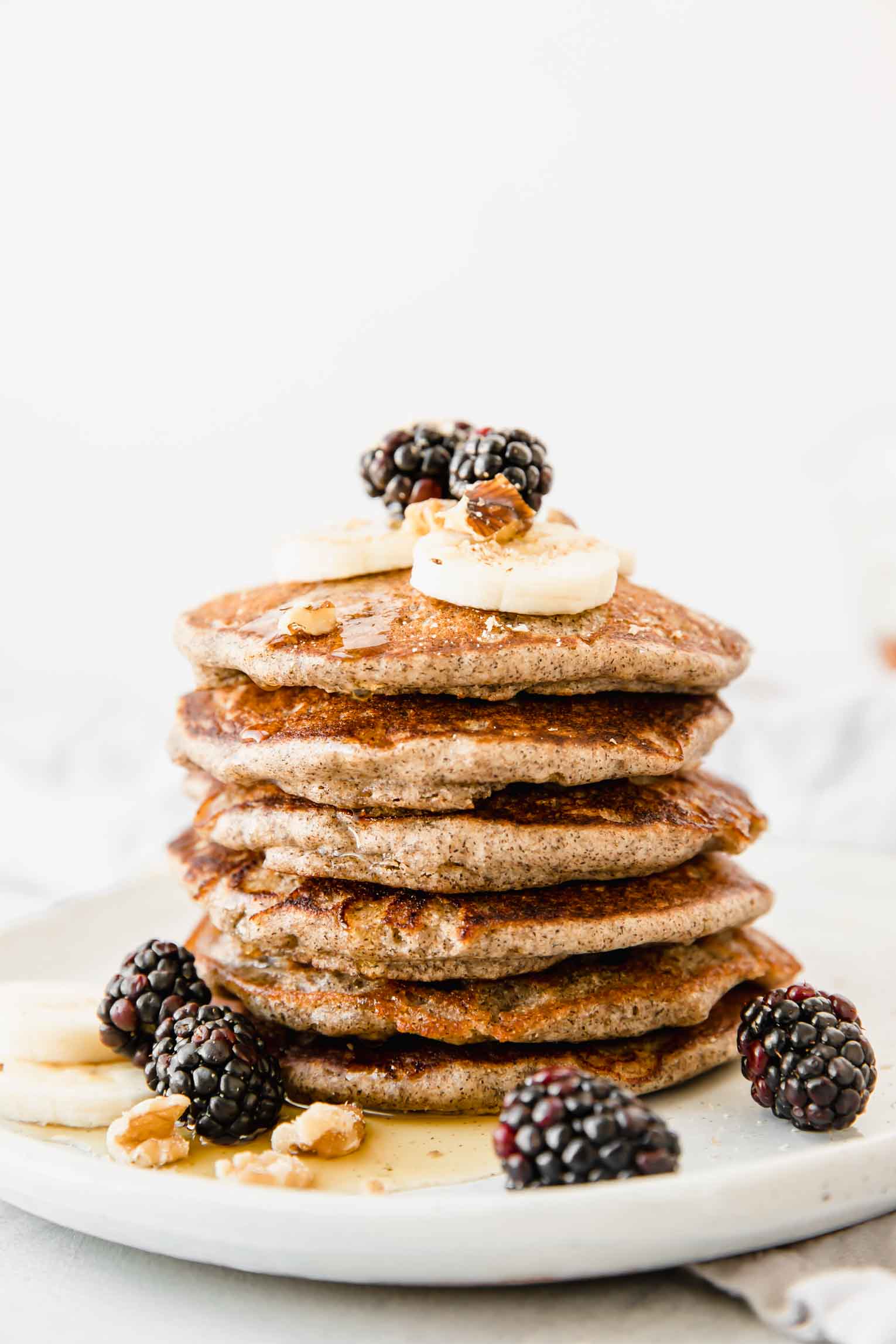 Stack of Buckwheat Pancakes w/ Pomegranate Compote on a white plate.