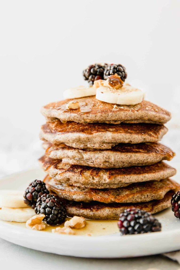 Vegan pancake stack on a white plate with blueberries.