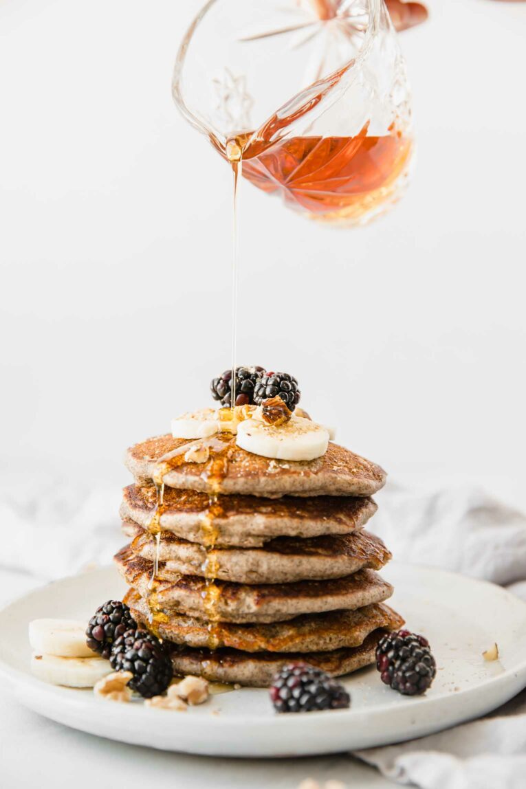 Buckwheat Pancakes with maple syrup being poured on them.