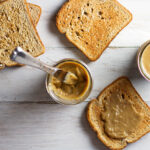 Homemade Kaya Coconut Egg Jam in a glass jar with a knife and toast at the side