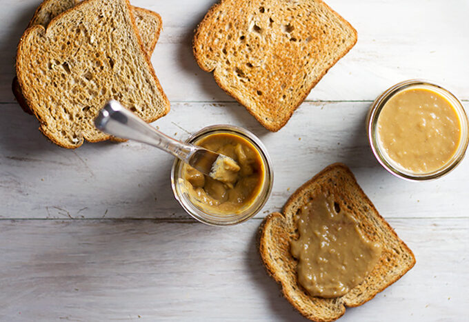 Homemade Kaya Coconut Egg Jam in a glass jar with a knife and toast at the side