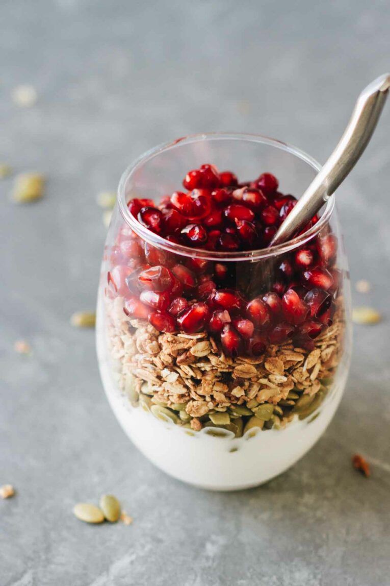 Pomegranate Breakfast Parfait in a glass with a spoon