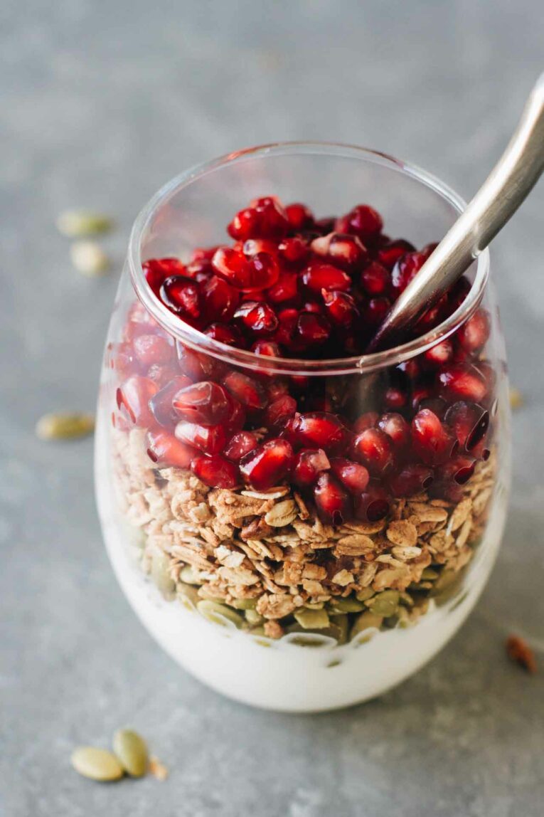 Pomegranate Breakfast Parfait in a glass with a spoon