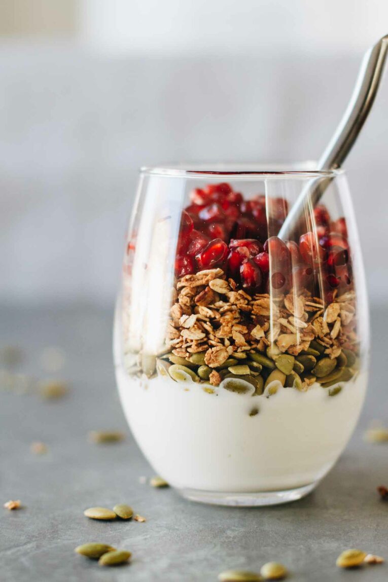 Pomegranate Breakfast Parfait in a glass with a spoon
