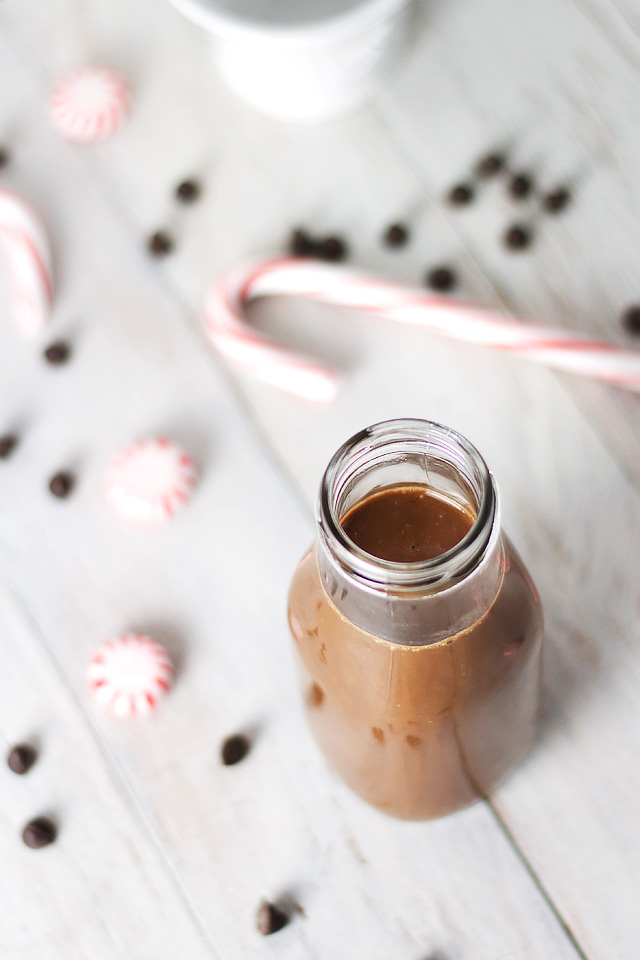 A Skinny Iced Peppermint Mocha on a white wooden surface with candy canes in the background