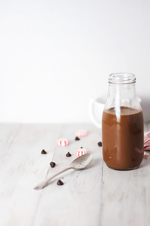 A Skinny Iced Peppermint Mocha in a glass milk bottle with a spoon at the side