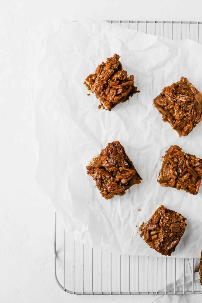 Overhead shot of The BEST Pecan Pie Bars scattered on parchment paper on a cooling rack.