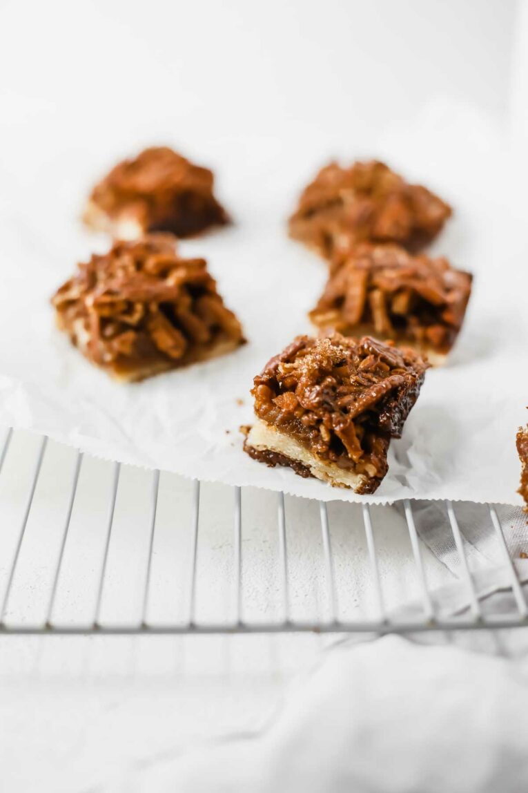The BEST Pecan Pie Bars scattered on parchment paper on a cooling rack.