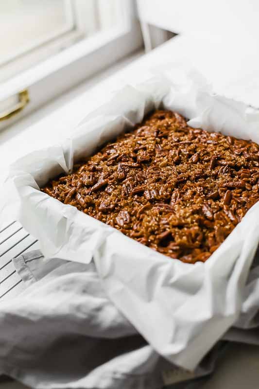 The BEST Pecan Pie Bars in a baking dish next to a window.