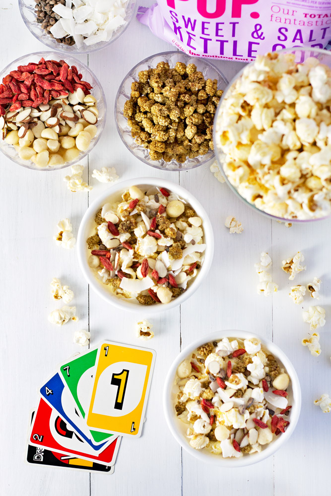 Popcorn party mix on a table with cards for game night.