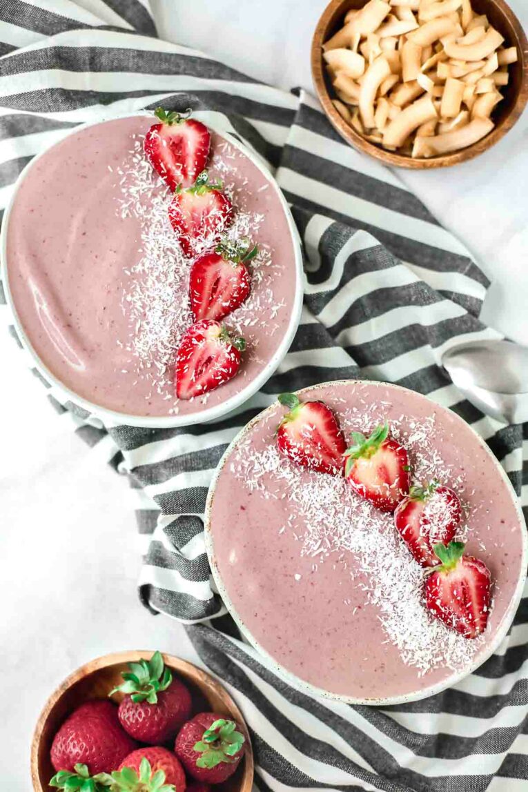 Two Strawberry Acai Smoothie Bowl on a striped towel and marble table. Yum!