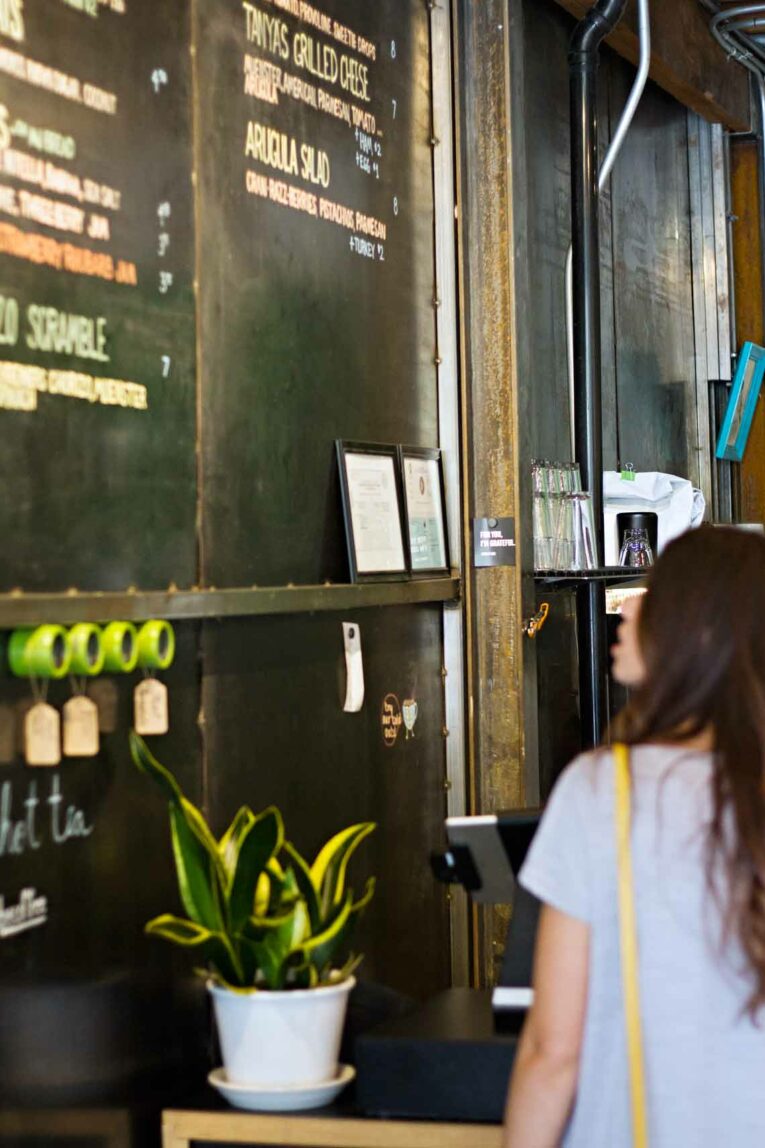 girl standing in front of large black menu 