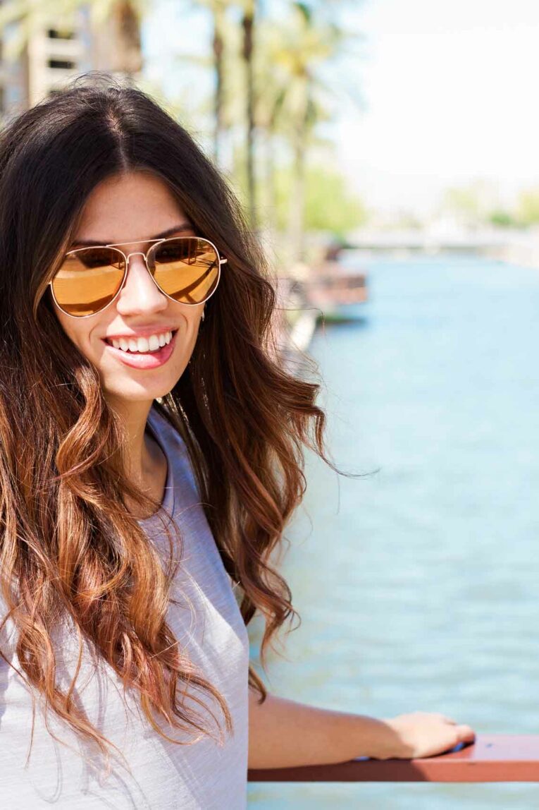 girl with sunglasses standing in front of water
