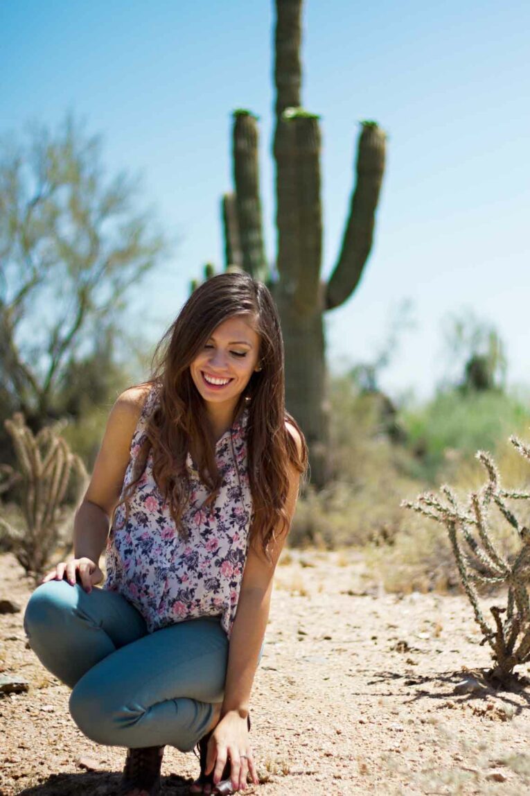 girl in desert squatting near cactus