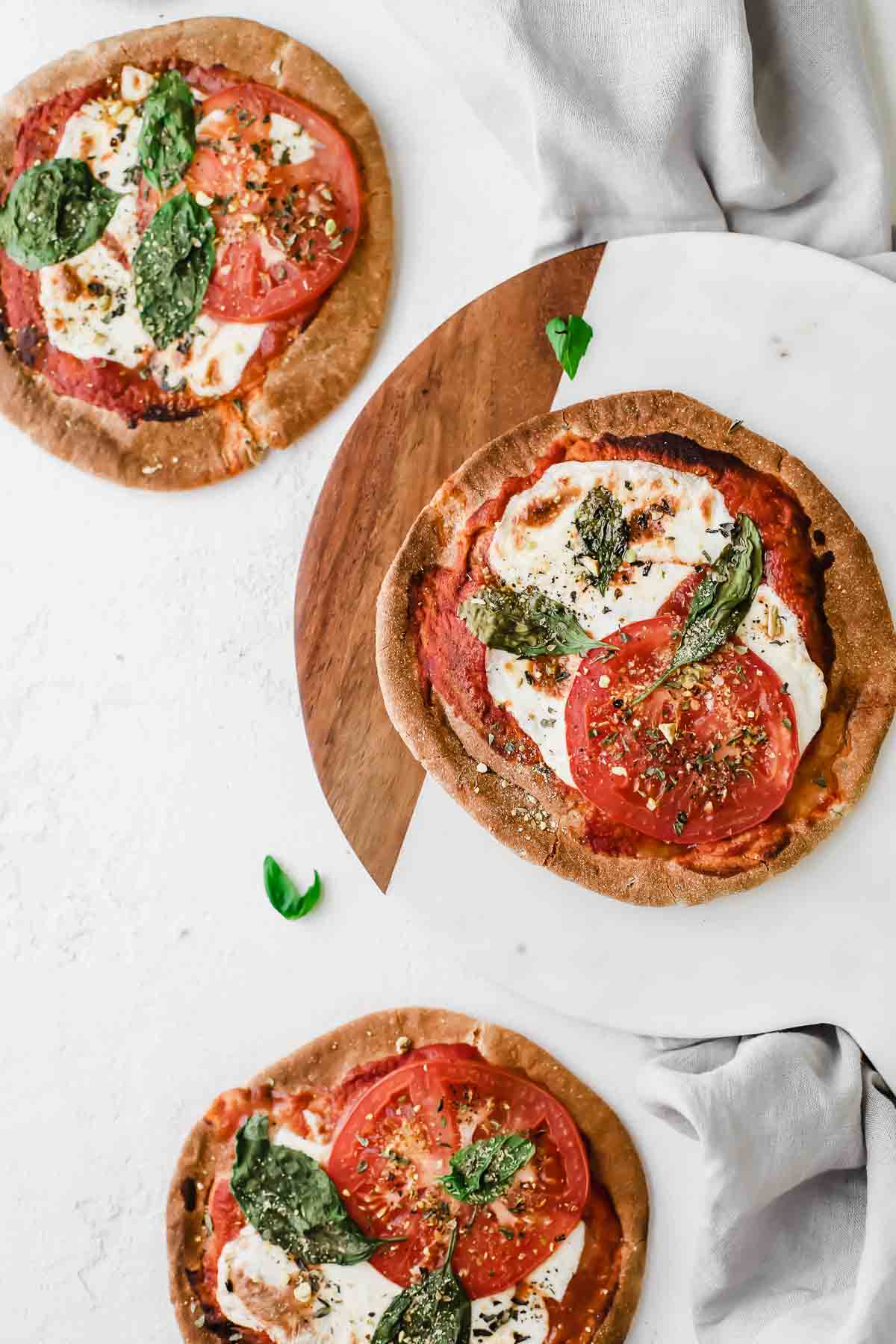 Overhead shot of Three Margherita Pita Bread Pizzas topped with mozzarella and basil