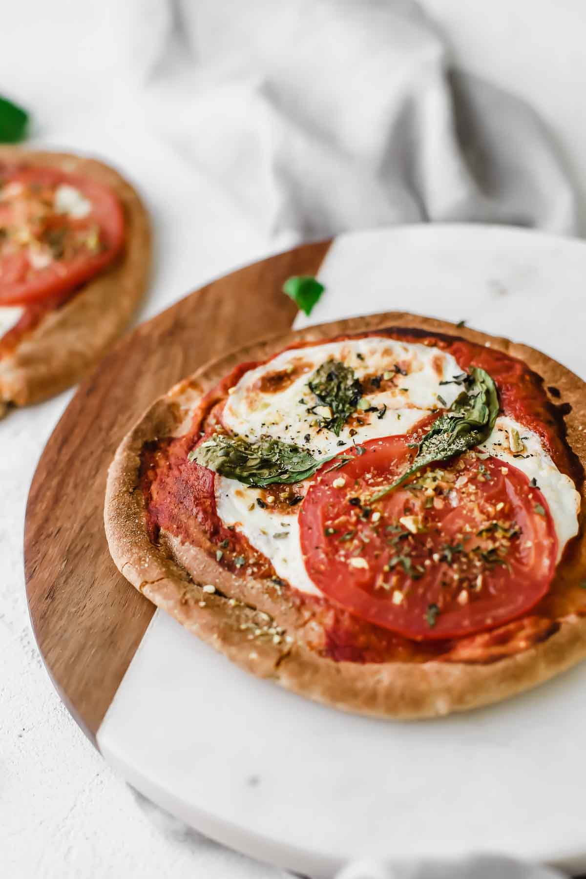 Margherita Pita Bread Pizzas  on a cutting board topped with fresh basil