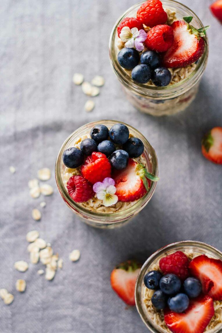 An overhead shot of overnight oats in mason jars with fresh berries
