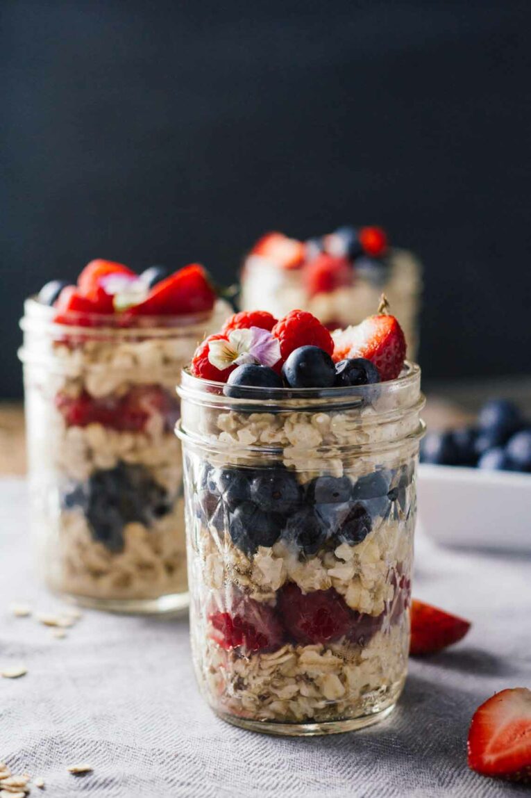 A close up of overnight oats in a mason jar topped with berries