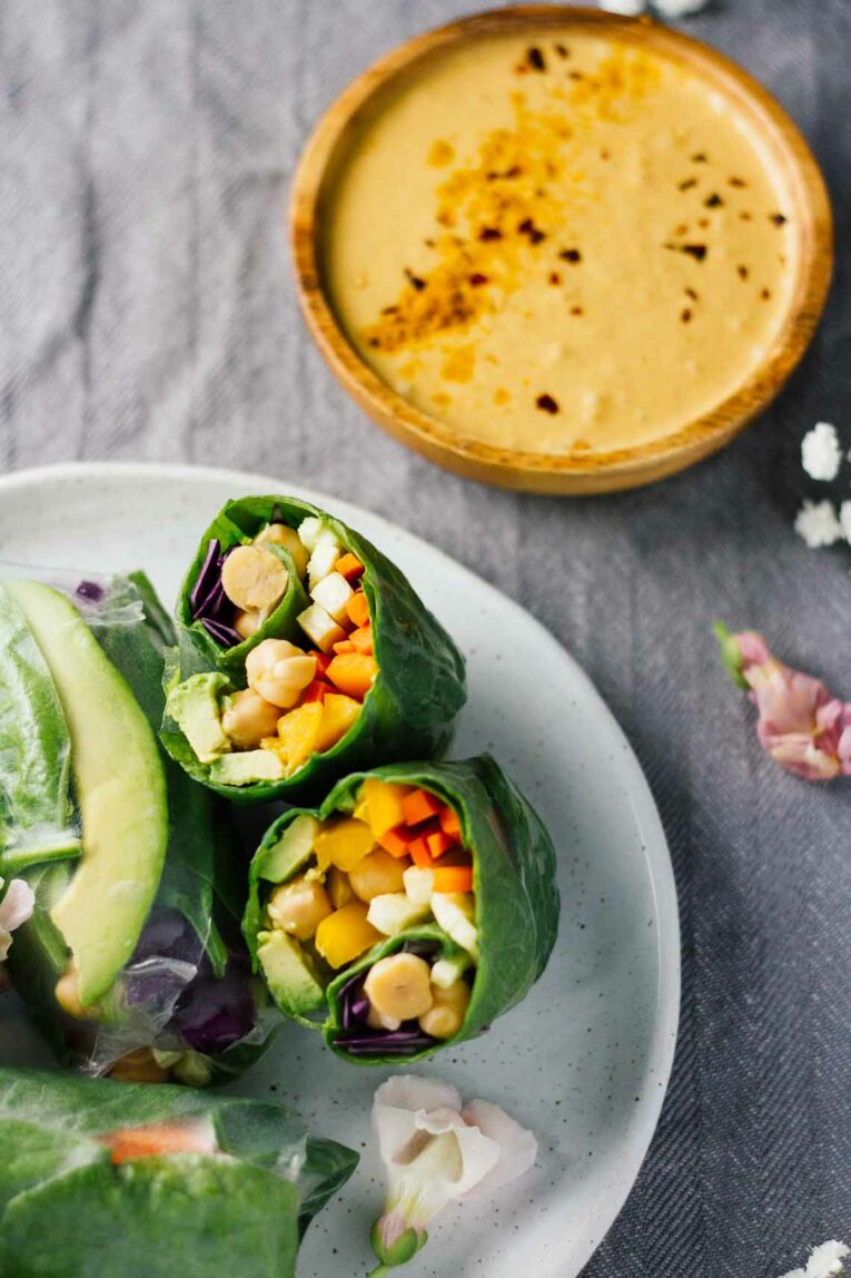 Vegan Spring Rolls on a white plate w/ Spicy Turmeric Coconut Sauce in a wooden bowl