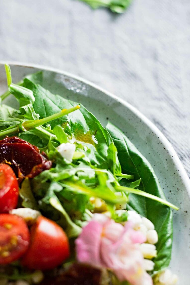 close up shot of a salad on a white speckled plate