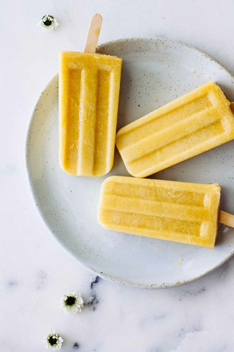Coconut Peach Turmeric Popsicles laid on a plate