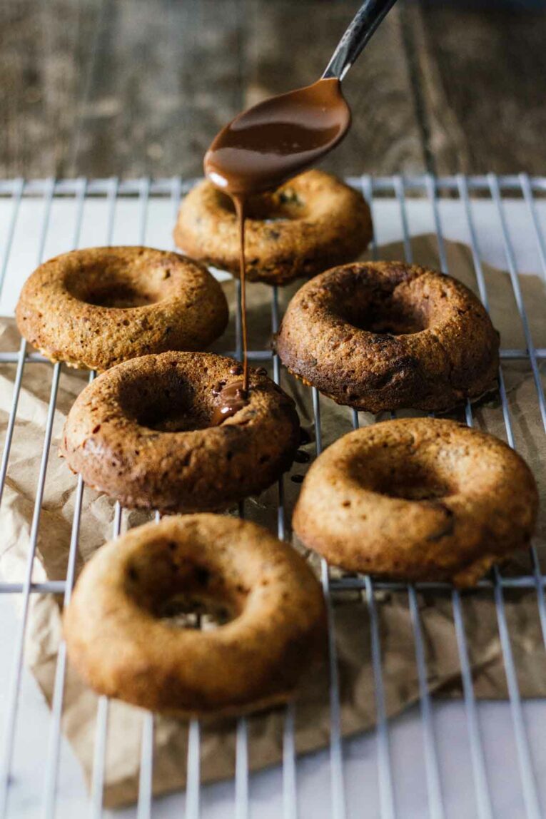 The easiest healthy donuts with peanut butter and chocolate that are made in a blender. These chocolate treats are not only super easy to whip up but they are healthy too! Get your chocolate donut fix minus the guilt and in only 25 minutes! #Jaroflemons #donuts #healthydonuts Healthy donuts with peanut butter and chocolate on a cooling rack