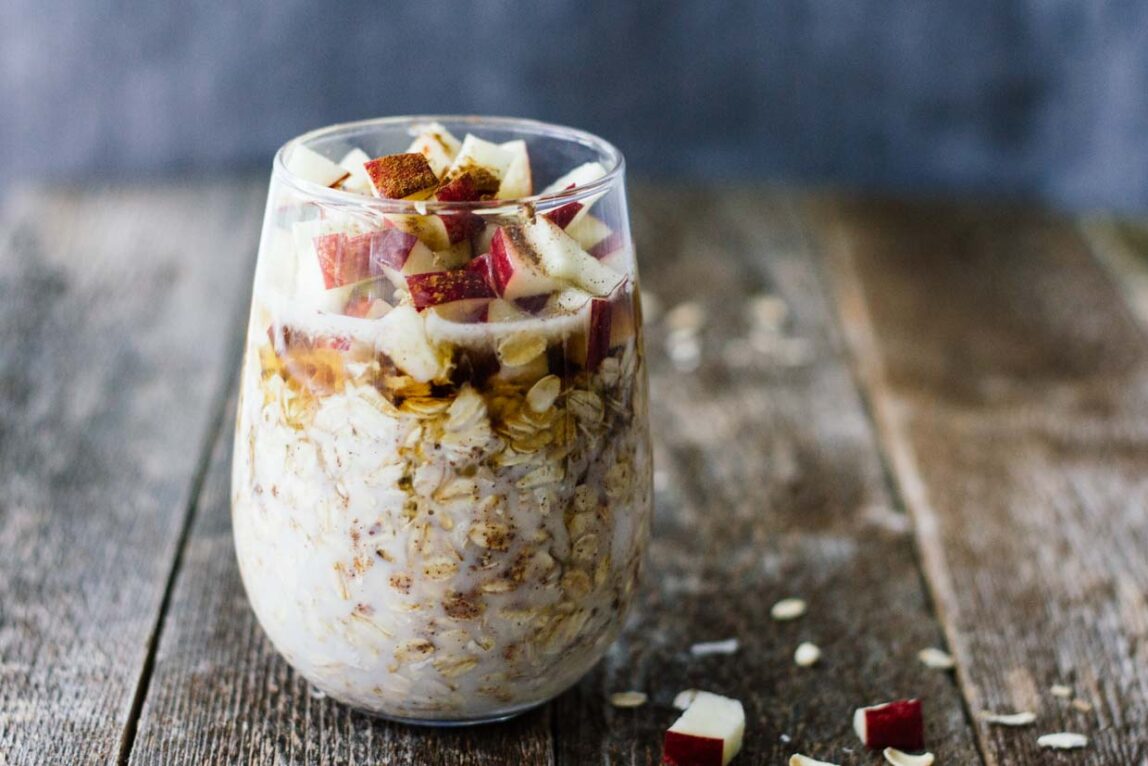 Apple Cinnamon Overnight Oats in a glass on a wooden surface.
