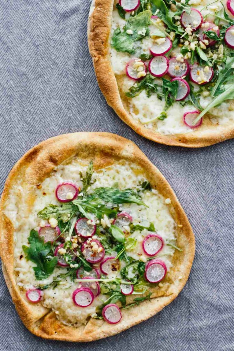 Roasted Radish, Arugula, & Havarti Pita Bread Pizzas on a grey background