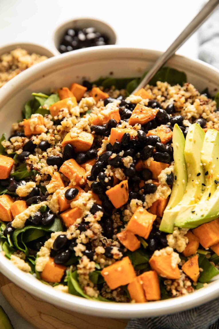 Roasted sweet potato black bean salad with avocado and quinoa in a grey bowl.