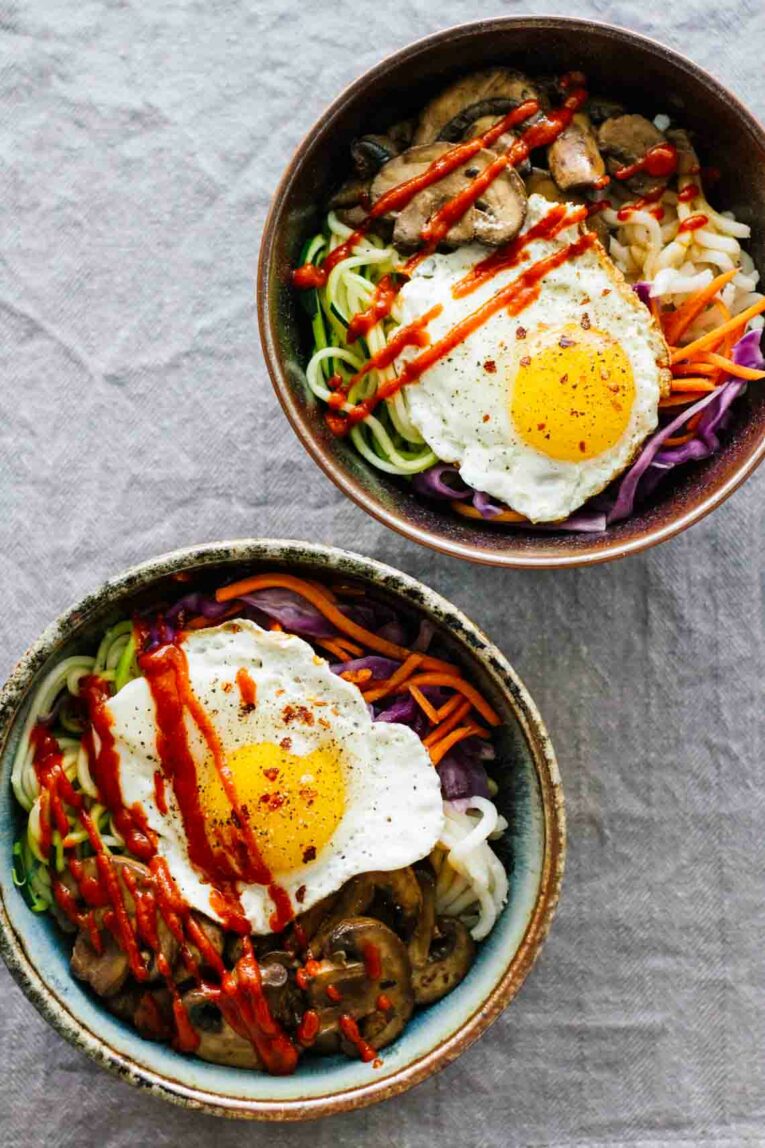 Top view of Vegetarian Spicy Korean Bibimbap Bowls on grey background