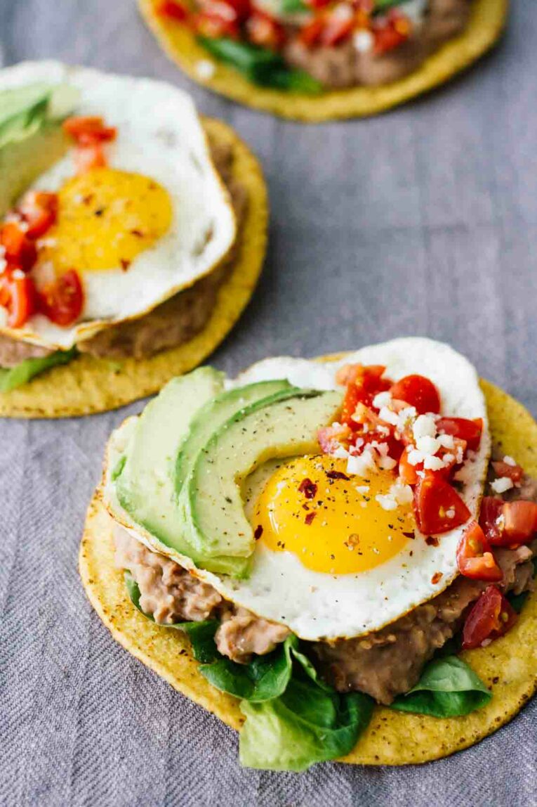 A close up of Huevos Rancheros with a fried egg, beans and tomatoes