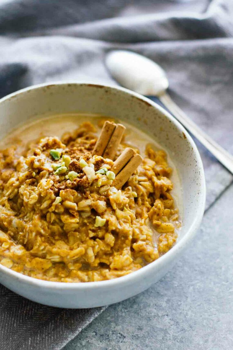 Pumpkin Pie Oatmeal in a Grey Bowl Topped with Pistachios and Cinnamon Sticks