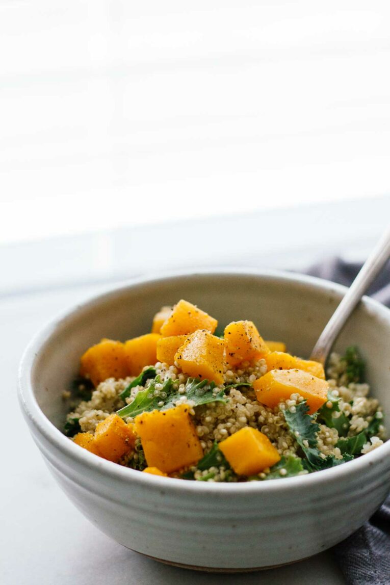 Roasted Butternut Squash & Garlic Quinoa in a white bowl with a fork