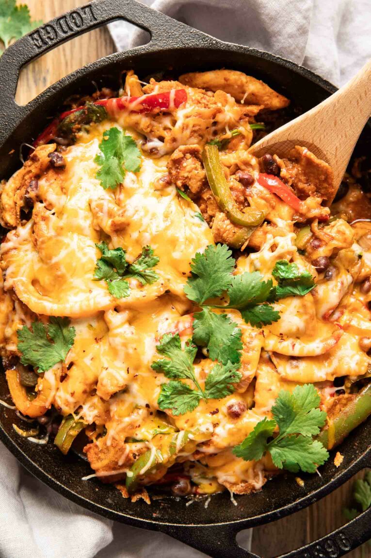 Chicken Fajita Casserole topped with cheese and fresh cilantro in a white, round casserole dish.