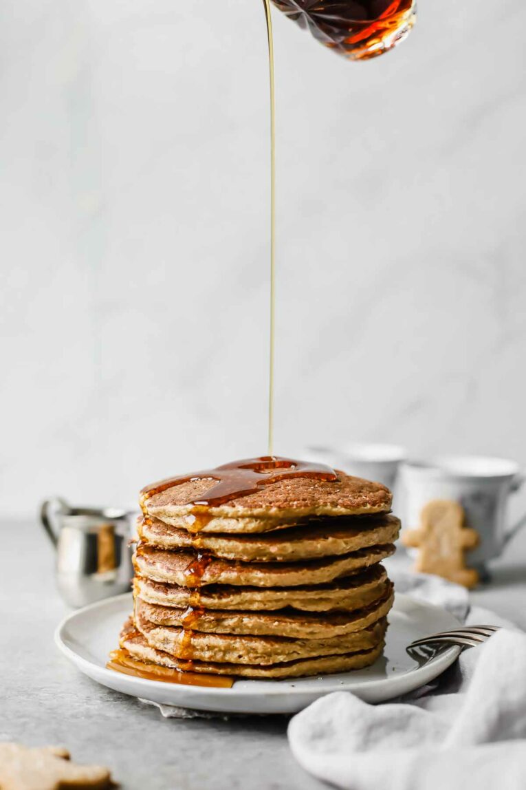 Syrup being poured over stack of Sweet, wholesome, Healthy Gingerbread Oatmeal Pancakes on a plate.