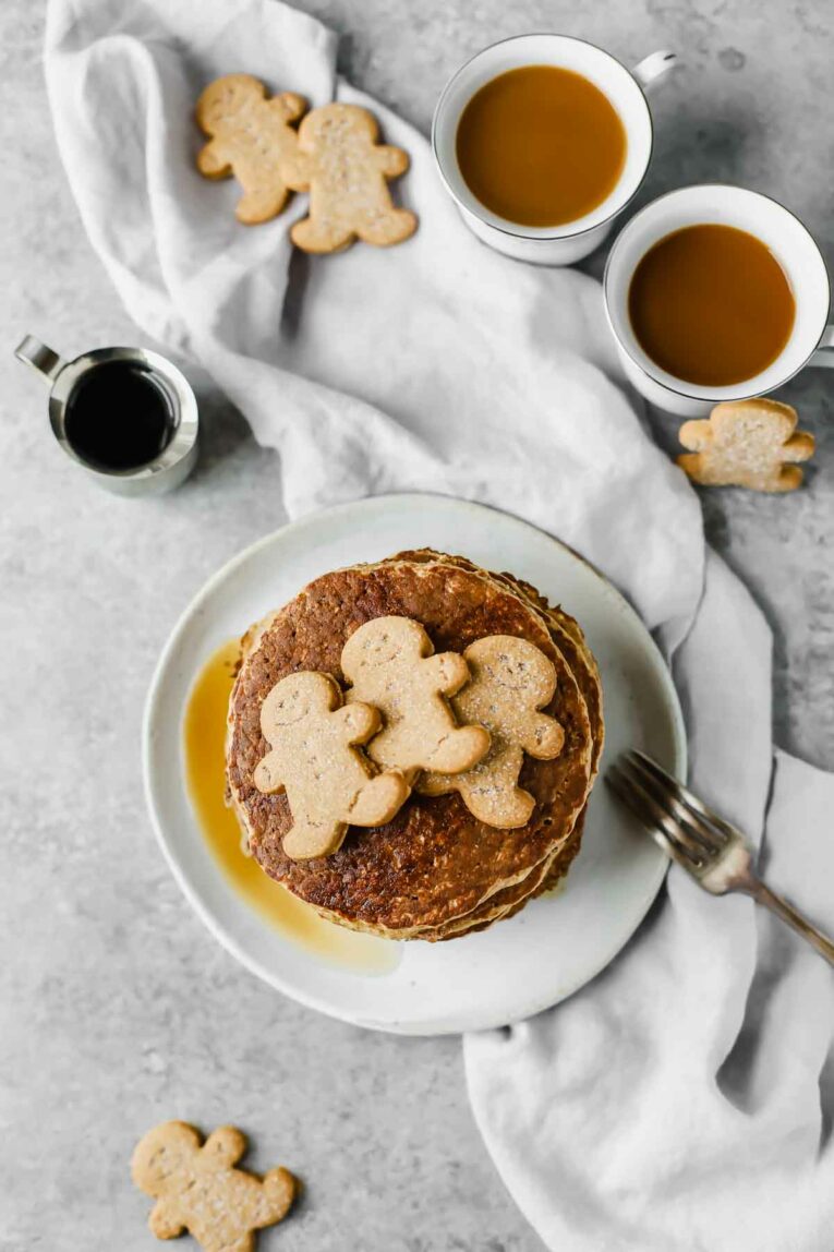 Overhead shot of Sweet, wholesome, Healthy Gingerbread Oatmeal Pancakes with 3 gingerbread man cookies on top.