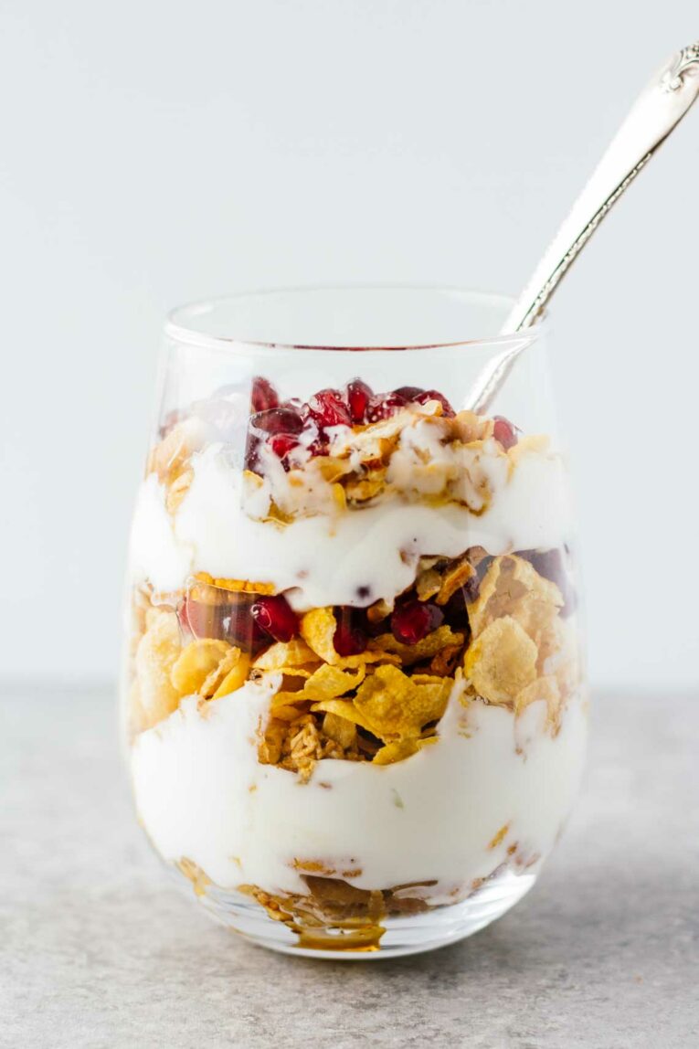 Pomegranate Pecan Breakfast Parfait in a glass with a spoon