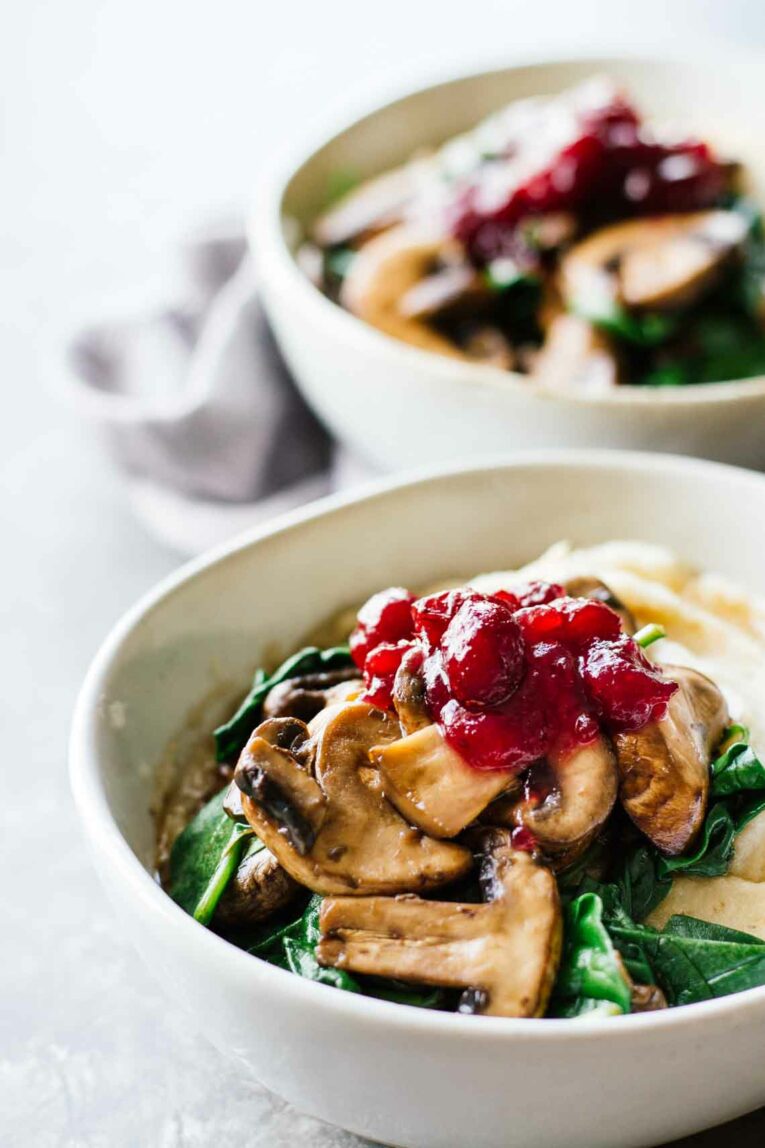 Slow Cooker Mashed Potatoes & Cranberry Mushroom Sauce in two white bowls