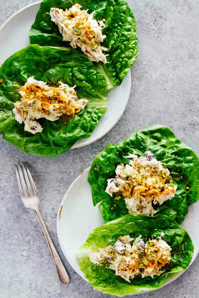 Overhead shot of Turmeric Greek Yogurt Chicken Salad Lettuce Wraps served on two white plates next to a fork