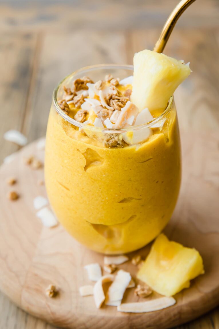 Golden Glow Pineapple Turmeric Smoothie in a glass with a blue straw
