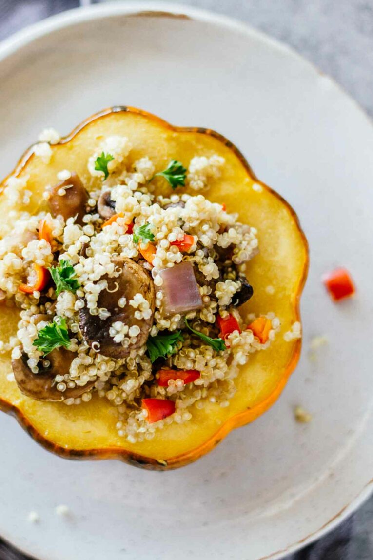 Overhead shot of Quinoa & Mushroom Stuffed Acorn Squash cut in half on a white plate