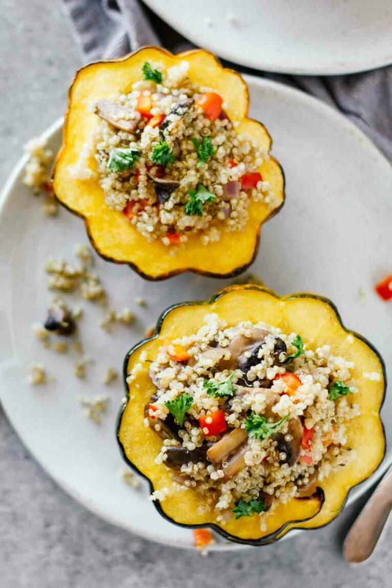 Overhead shot of Quinoa & Mushroom Stuffed Acorn Squash cut in half on a white plate