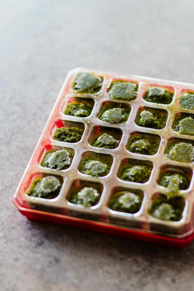 An overhead shot of chopped basil in frozen cubes in a tray