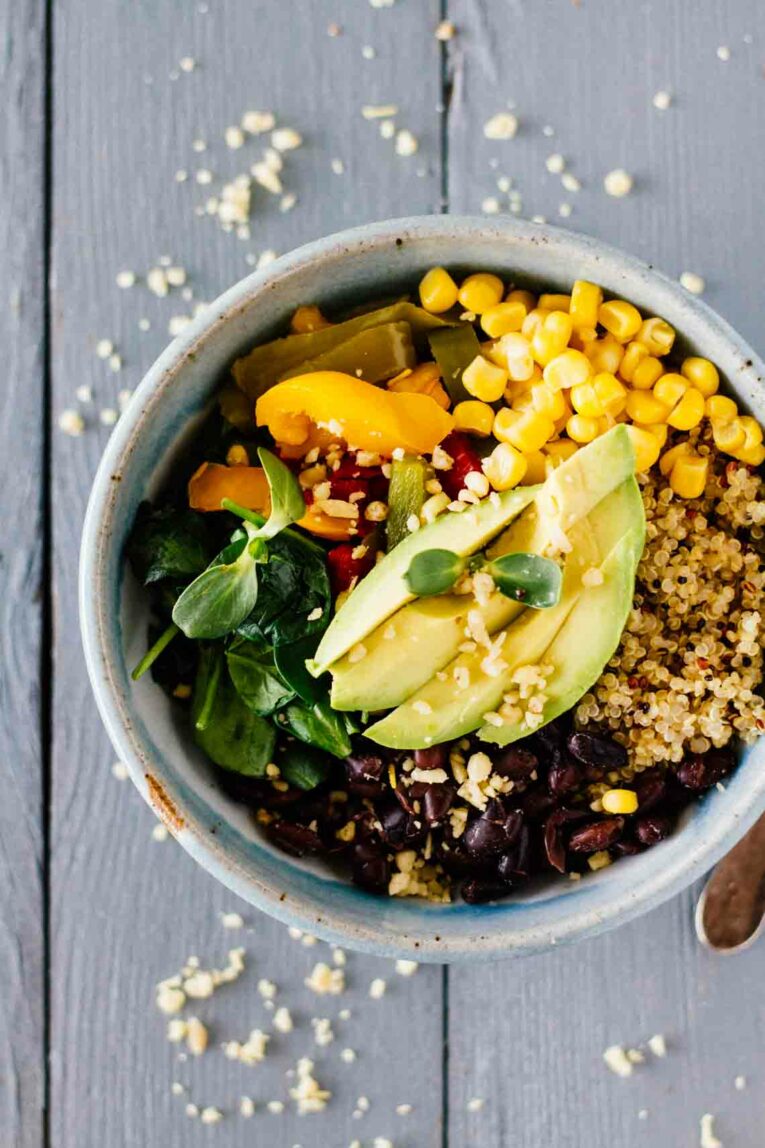 Vegan Meal-Prep Black Bean Quinoa Bowls with corn, peppers, and fresh sprouts.